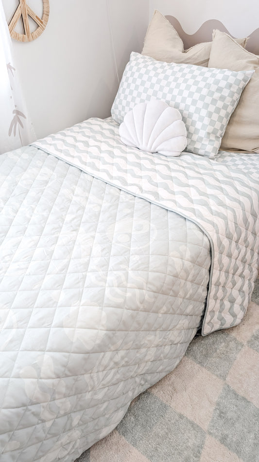 A neutral and coastal kids bed made with organic cotton sheets and organic cotton reversible quilt blanket with wavy stripe print completes this cute coastal kids bedding linen look | The Cuddle Collective