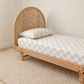 beige and white checkered organic cotton fitted sheet and pillow on a textured cream rug against a neutral beige wall.
