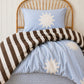 a brown stripe and sun print quilt cover made with organic cotton, for the cuddle collective. a beautiful kids bedding set