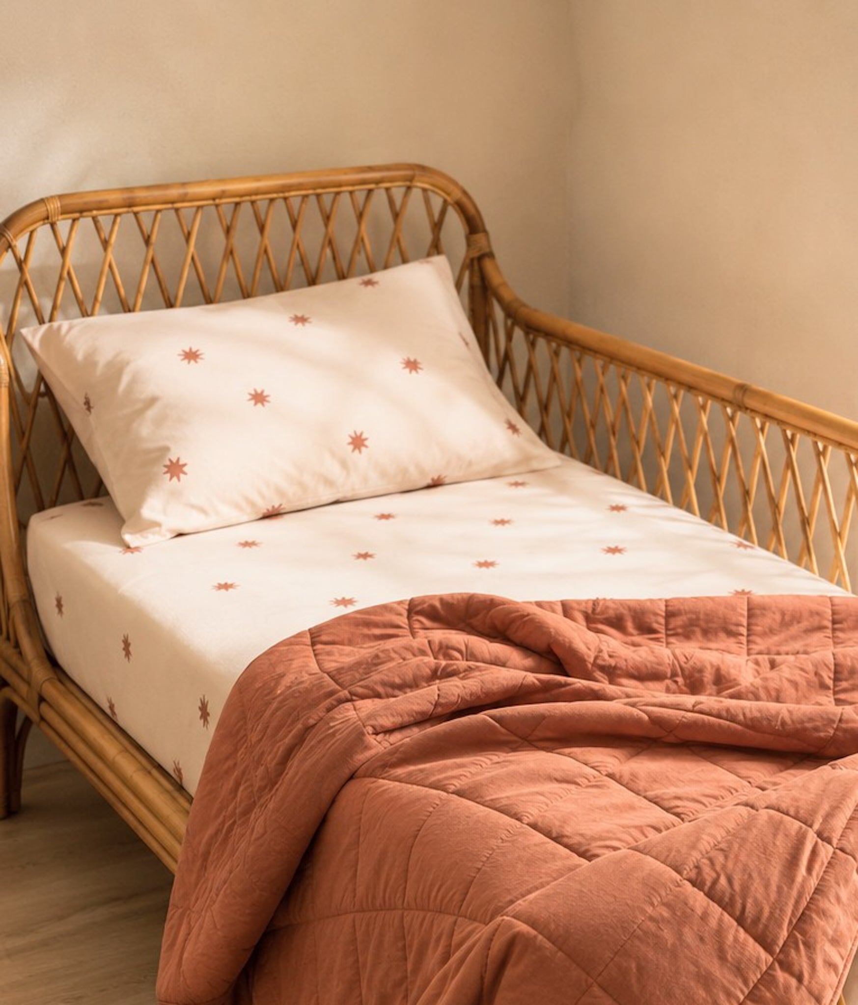 Star organic cotton fitted sheet paired with a teracotta reversible kids quilt