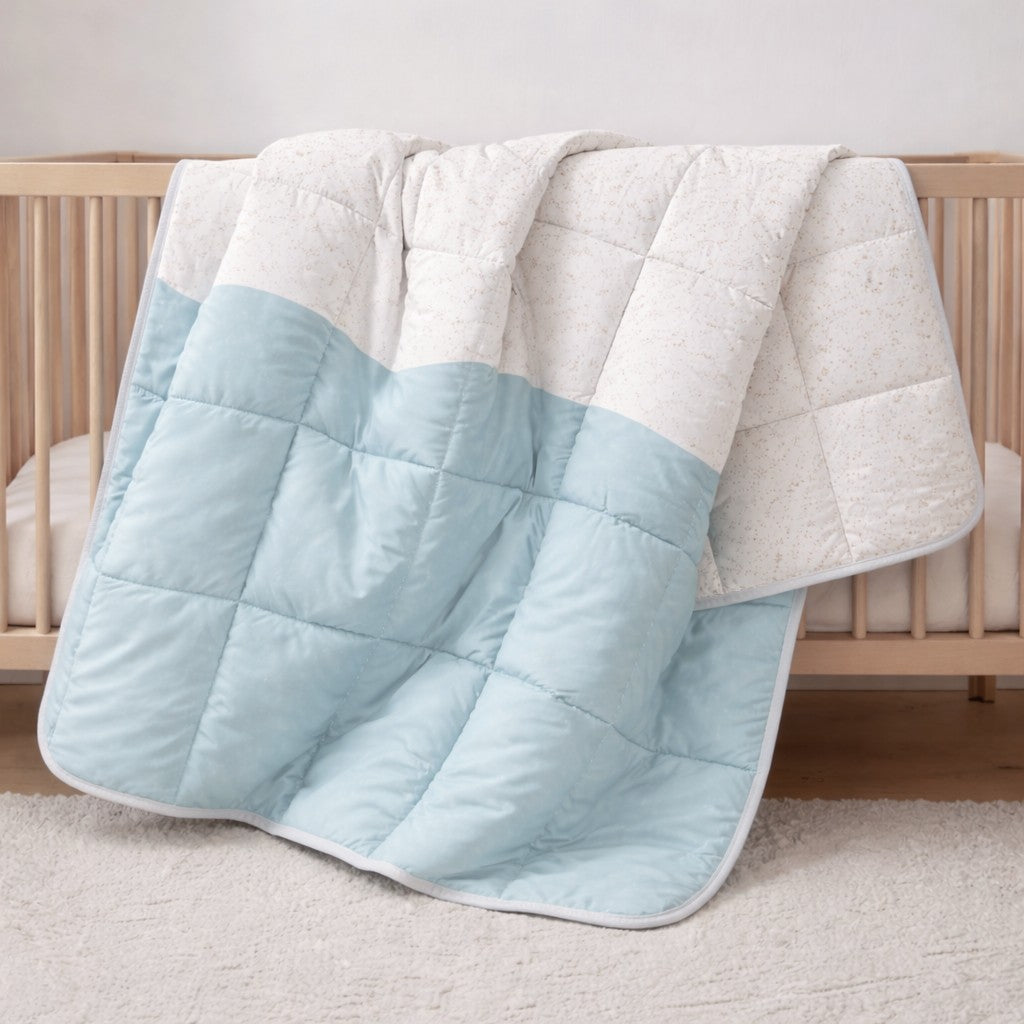 Baby blue wave and speckle reversible quilt hanging on a bed in a kids bedroom