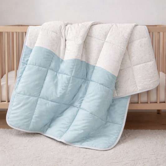 Baby blue wave and speckle reversible quilt hanging on a bed in a kids bedroom