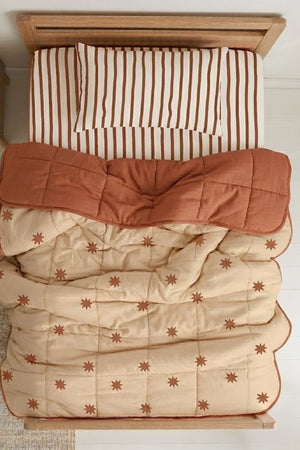 Starfall quilt styled with Coco Stripe organic cotton sheets on a kids bed