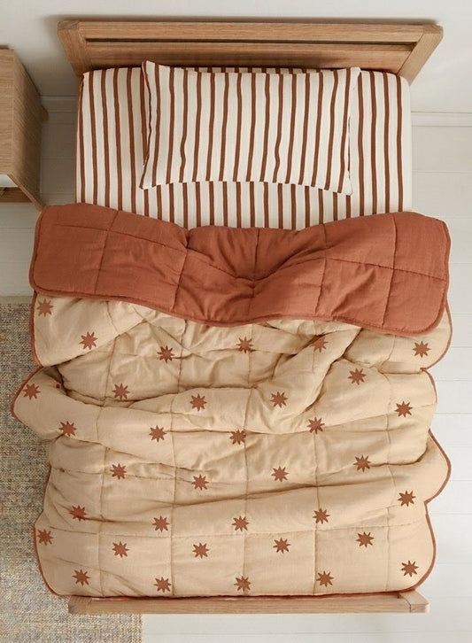Starfall quilt styled with Coco Stripe organic cotton sheets on a kids bed