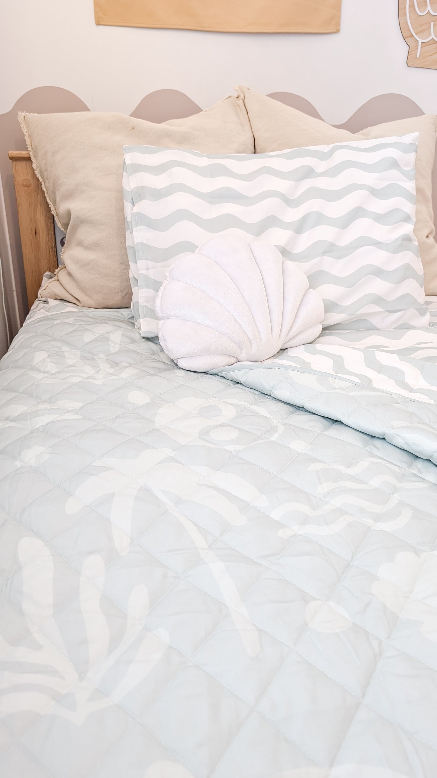 A neutral and coastal kids bed made with organic cotton sheets and organic cotton reversible quilt blanket with wavy stripe print completes this cute coastal kids bedding linen look | The Cuddle Collective