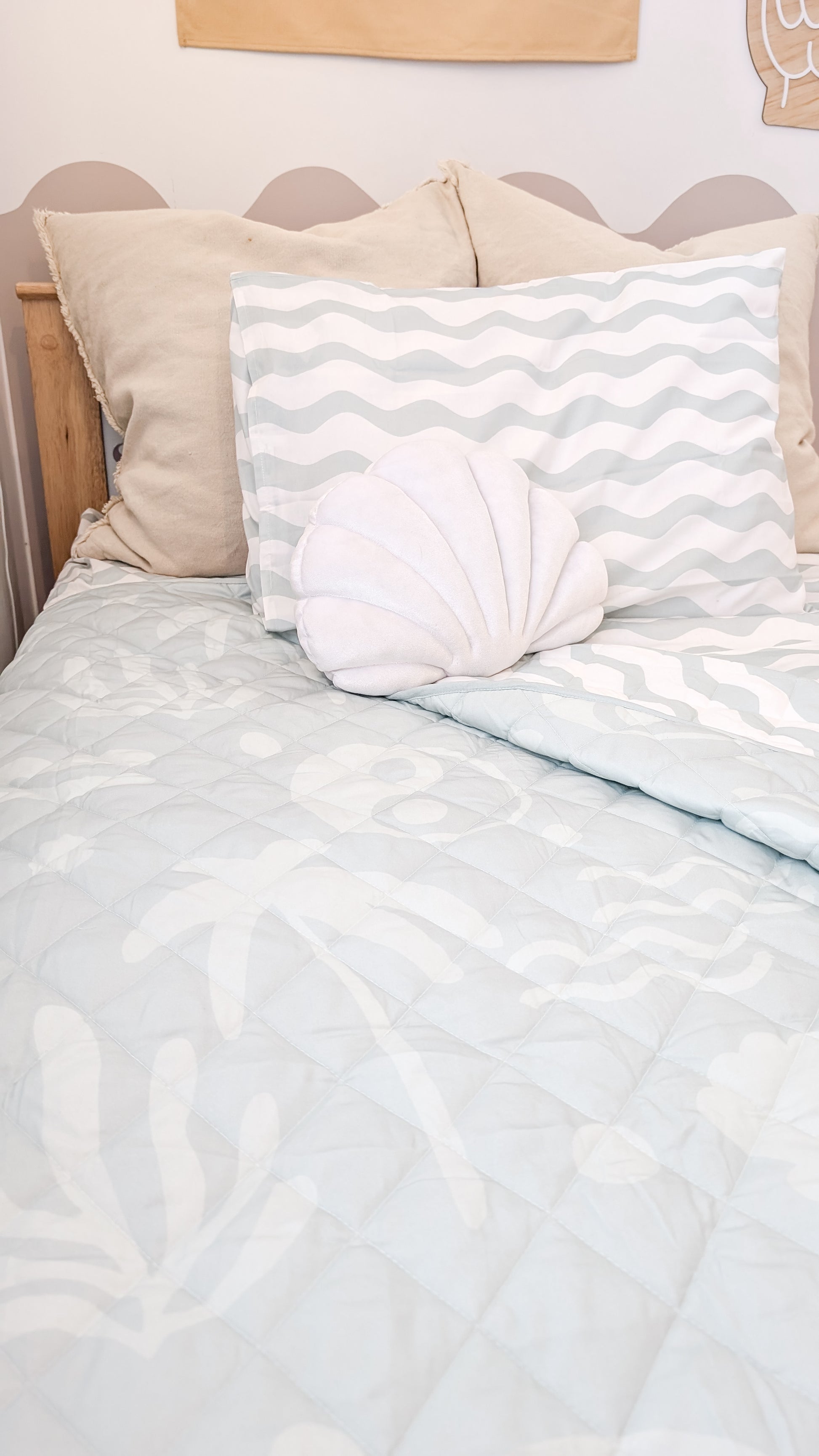 A neutral and coastal kids bed made with organic cotton sheets and organic cotton reversible quilt blanket with wavy stripe print completes this cute coastal kids bedding linen look | The Cuddle Collective