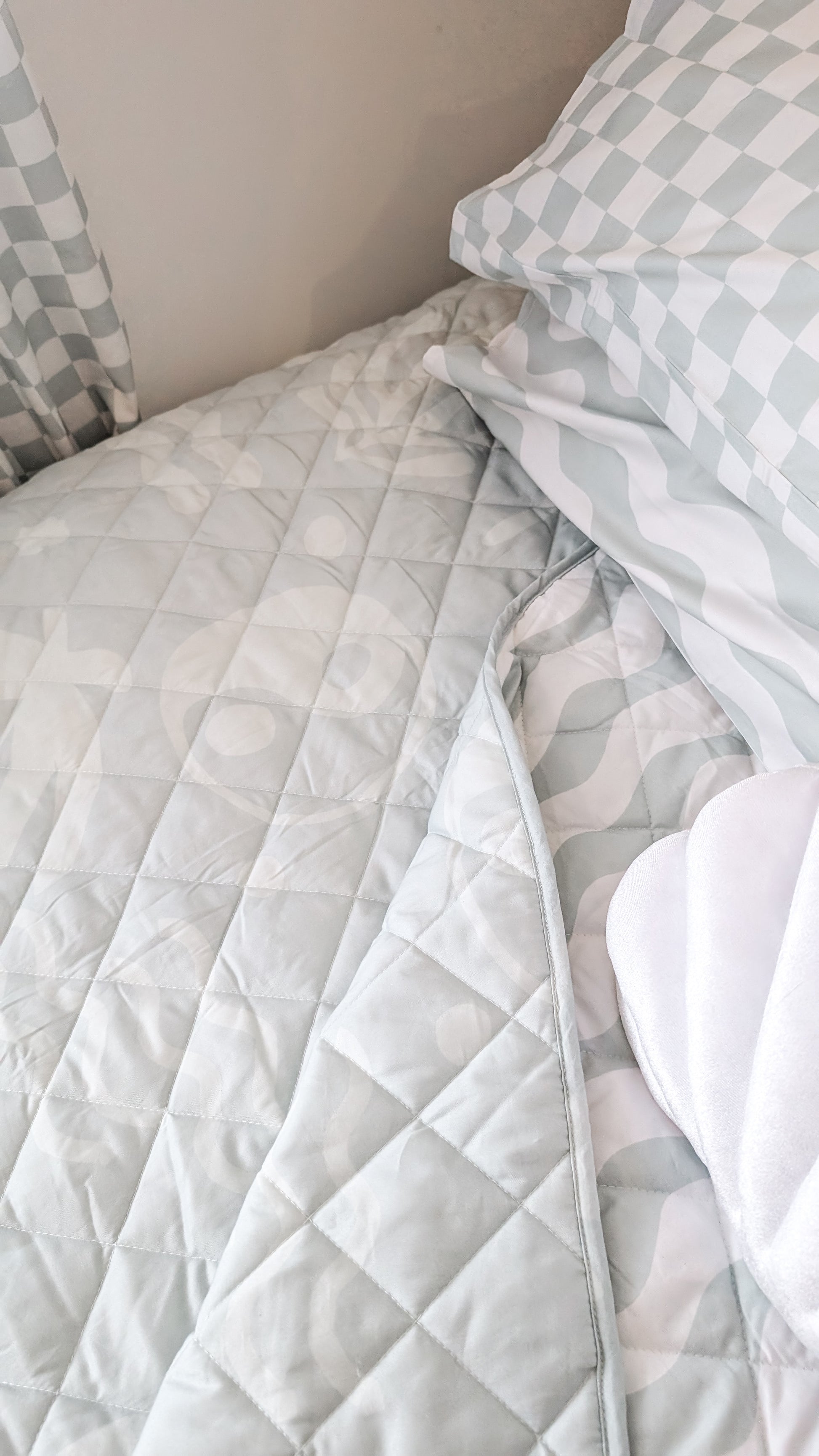 A neutral and coastal kids bed made with organic cotton sheets and organic cotton reversible quilt blanket with wavy stripe print completes this cute coastal kids bedding linen look | The Cuddle Collective