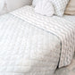 A neutral and coastal kids bed made with organic cotton sheets and organic cotton reversible quilt blanket with wavy stripe print completes this cute coastal kids bedding linen look | The Cuddle Collective