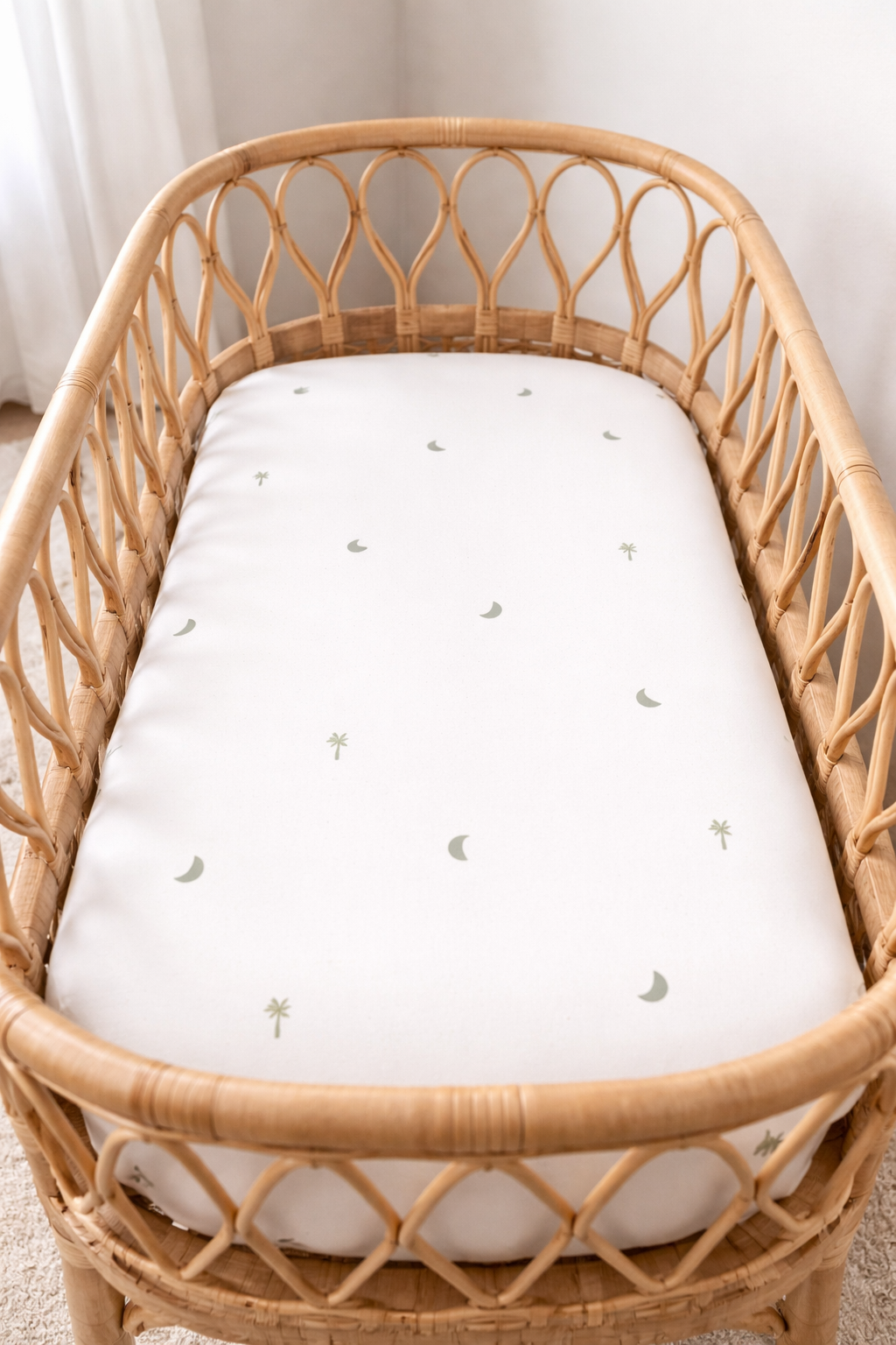 organic cotton sage palm and moon print cot sheets in a cot