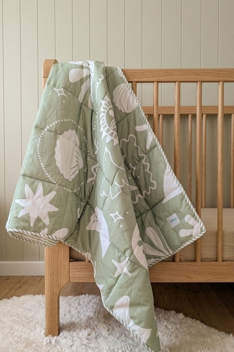organic cotton sage reversible quilt in a nursery