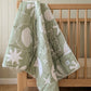 organic cotton sage reversible quilt in a nursery