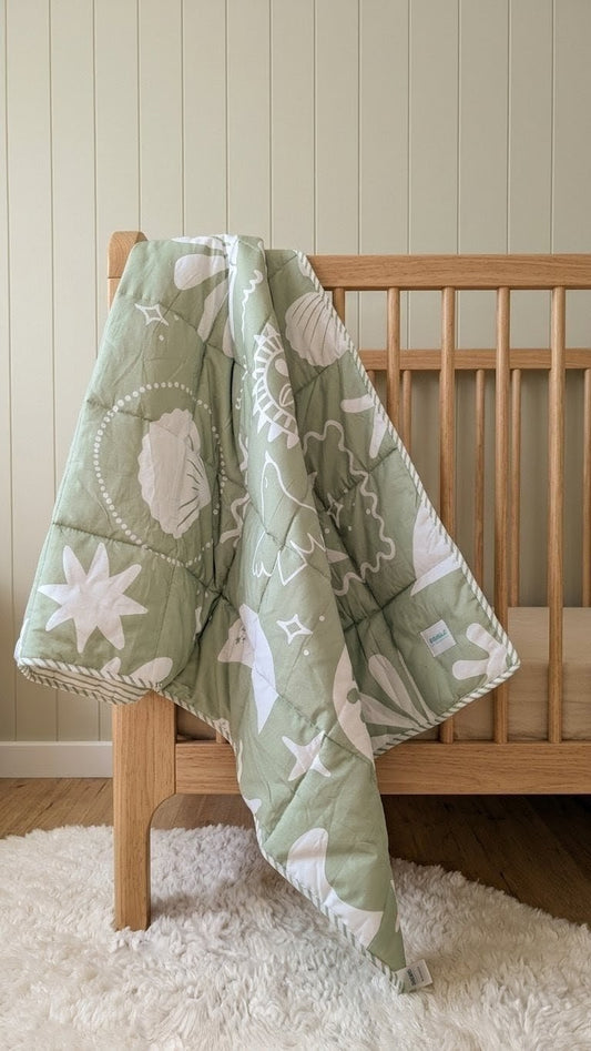 organic cotton sage reversible quilt in a nursery